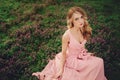 Beautiful blonde young woman in colorful flowers. girl with make-up and hairstyle in pink dress in blossoming spring park. Art Royalty Free Stock Photo