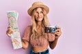 Beautiful blonde young woman holding city map and vintage camera angry and mad screaming frustrated and furious, shouting with Royalty Free Stock Photo