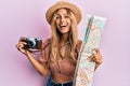 Beautiful blonde young woman holding city map and vintage camera smiling and laughing hard out loud because funny crazy joke Royalty Free Stock Photo