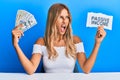 Beautiful blonde young woman holding dollars and passive income text angry and mad screaming frustrated and furious, shouting with