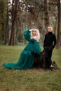 A beautiful blonde young woman in a long green dress and a diadem on her head with stylish young son in the forest. girl and boy Royalty Free Stock Photo