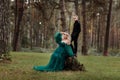 A beautiful blonde young woman in a long green dress and a diadem on her head with stylish young son in the forest. girl and boy Royalty Free Stock Photo