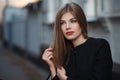 Beautiful blonde young woman in nice black coat. Posing on urban background. Fashion Photo