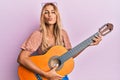 Beautiful blonde young woman playing classical guitar looking at the camera blowing a kiss being lovely and sexy Royalty Free Stock Photo