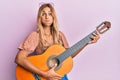 Beautiful blonde young woman playing classical guitar puffing cheeks with funny face Royalty Free Stock Photo