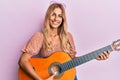 Beautiful blonde young woman playing classical guitar smiling with a happy and cool smile on face Royalty Free Stock Photo