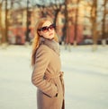 Beautiful blonde young woman posing in sunglasses, winter coat outdoors in park Royalty Free Stock Photo