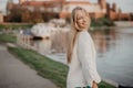 Beautiful blonde young woman walking beside the river at sunset have fun smile and play on camera Royalty Free Stock Photo