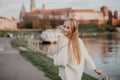 Beautiful blonde young woman walking beside the river at sunset have fun smile and play on camera Royalty Free Stock Photo