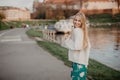 Beautiful blonde young woman walking beside the river at sunset have fun smile and play on camera Royalty Free Stock Photo