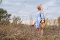 Beautiful blondie woman with trendy nude rattan round bag walking outdoors. Royalty Free Stock Photo