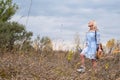 Beautiful blondie woman with trendy nude rattan round bag walking outdoors. Royalty Free Stock Photo