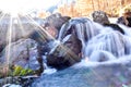 Beautiful blue Alpine waterfall in mountain forest with sun flare Royalty Free Stock Photo