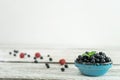 A beautiful blue bowl full of ripe blueberries stands on a light wooden table against a white wall. Royalty Free Stock Photo