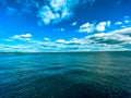 Beautiful blue and cloudy sky over a calm ocean. Royalty Free Stock Photo