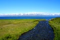 A beautiful blue creek overlooking partially covered snowy mountain and the fjord in the summer near Hofn, Iceland