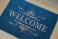 Beautiful blue doormat with word Welcome on floor near entrance, above view