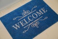 Beautiful blue doormat with word Welcome on floor near entrance, above view