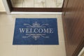 Beautiful blue doormat with word Welcome on floor near entrance, above view