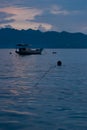 Beautiful blue early morning on calm sea with smooth waves, sky with fluffy clouds, blue mountains in haze, float boat, buoys. Royalty Free Stock Photo