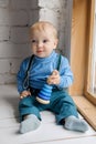 Beautiful blue-eyed baby sitting on the windowsill with a toy pyramid Royalty Free Stock Photo