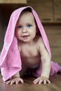 Beautiful blue-eyed baby smiles in a pink towel