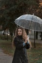 Beautiful blue-eyed girl with wavy hair looks wistfully to side. Young woman holding umbrella in hands. Vertical frame Royalty Free Stock Photo