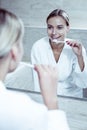 Beautiful blue-eyed woman looking in mirror while brushing her teeth Royalty Free Stock Photo