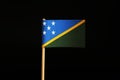 A beautiful blue and green Flag of the Solomon Islands on wooden stick on black background. Solomon Islands belongs to Oceania