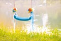 Beautiful blue hanging empty swing made of plastic on ropes, decorated with flowers and ribbons. The concept of dreams and