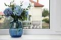 Beautiful blue hortensia flowers in vase on window sill indoors. Space for text Royalty Free Stock Photo
