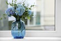 Beautiful blue hortensia flowers in vase on window sill indoors. Space for text Royalty Free Stock Photo