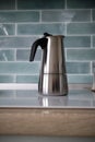 A stainless geyser coffee machine is on the electric stove.