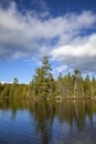 Beautiful blue lake in northern Minnesota with pines along the shore under blue sky and clouds Royalty Free Stock Photo