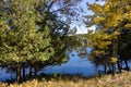 Beautiful blue lake seen through orange and green trees on a sunny fall day in Muskoka, Ontario Royalty Free Stock Photo