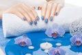 Beautiful blue manicure with orchid and towel on the white wooden table. spa Royalty Free Stock Photo