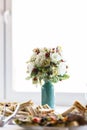 Beautiful blue shining vase of flowers near the white daylight window Royalty Free Stock Photo