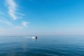 Beautiful blue sky with light white clouds. Boat cruising the sea leaving wake on a brilliant sunny day. Royalty Free Stock Photo