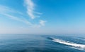 Beautiful blue sky with light white clouds. Boat cruising the sea leaving wake on a brilliant sunny day. Royalty Free Stock Photo