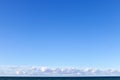 Beautiful blue sky over the sea with small cumulus clouds near the horizon Royalty Free Stock Photo