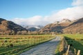 Beautiful blue sky winter morning in Valley of the Lake District on a farm path with snow on the tops