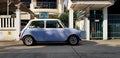 Beautiful Blue/White classic Mini cooper parked on the street  in front of home`s entrance door Royalty Free Stock Photo