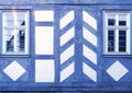 Beautiful blue windows and part of the wall of a wooden house, purple and white geometric pattern, half-timbered architecture