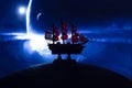 Beautiful boat toy over a blue balll with blurred blue deep universe scene at background.
