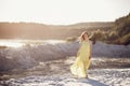 Beautiful boho girl walking on sandy beach at sunset light near Royalty Free Stock Photo