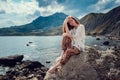 Beautiful boho styled model wearing white crochet swimsuit posing on the beach in sunlight Royalty Free Stock Photo
