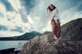 Beautiful boho styled model wearing white crochet swimsuit posing on the beach in sunlight Royalty Free Stock Photo