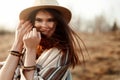 Beautiful boho woman hipster, smiling, wearing hat and poncho at sunset in mountains, true emotions, space for text