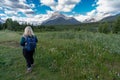 Beautiful bombshell blonde woman hiker contemplates and decides where to go next, in a grassy trail with wildflowers, in