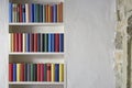 Beautiful bookshelf with colorful books in a white wall with stones in a loft